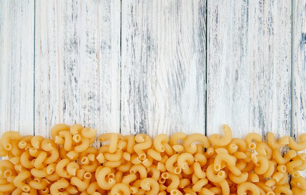 Vue de dessus des pâtes macaroni au coude sur le fond avec copie espace sur fond de bois blanc