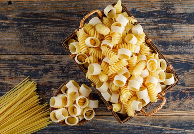 Vue de dessus des pâtes macaroni dans un panier avec des spaghettis sur fond de bois. horizontal