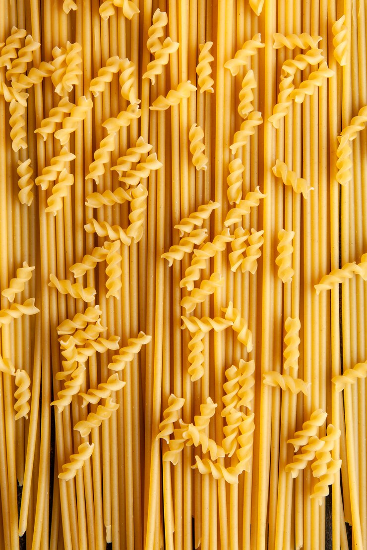 Photo gratuit vue de dessus des pâtes macaroni fusilli avec des spaghettis sur fond. verticale