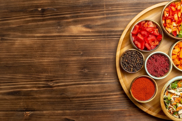 Vue de dessus pâtes de pâte crue avec différents assaisonnements sur le fond en bois brun pâte alimentaire repas de pâtes