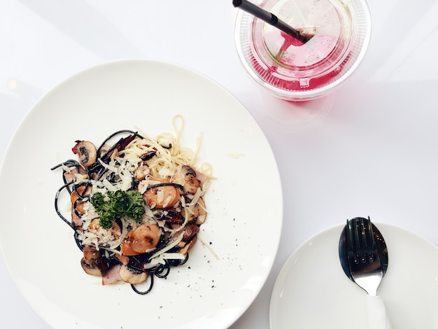 Vue de dessus des pâtes spaghetti aux tomates et au persil sur la table blanche.