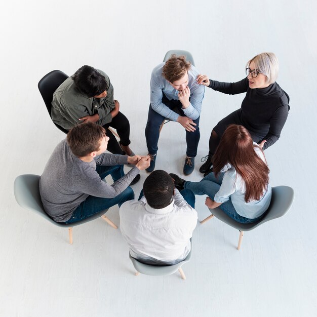 Vue de dessus des patients en réadaptation debout en cercle et parlant