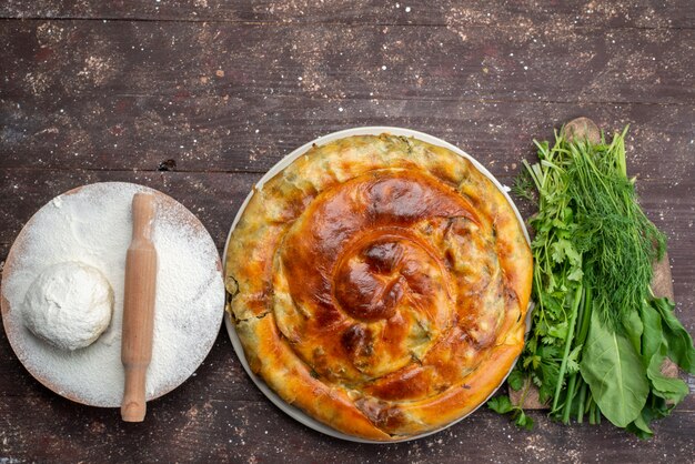 Vue de dessus de la pâtisserie de légumes verts cuits avec des légumes verts et de la pâte sur le pain de nourriture de bureau en bois brun