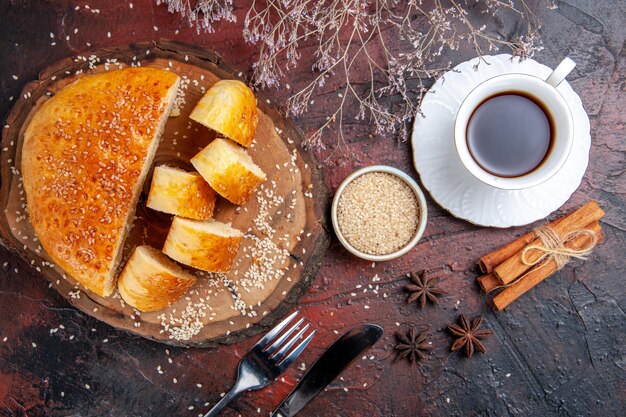 Vue de dessus de la pâtisserie sucrée coupée en morceaux avec du thé sur une surface sombre