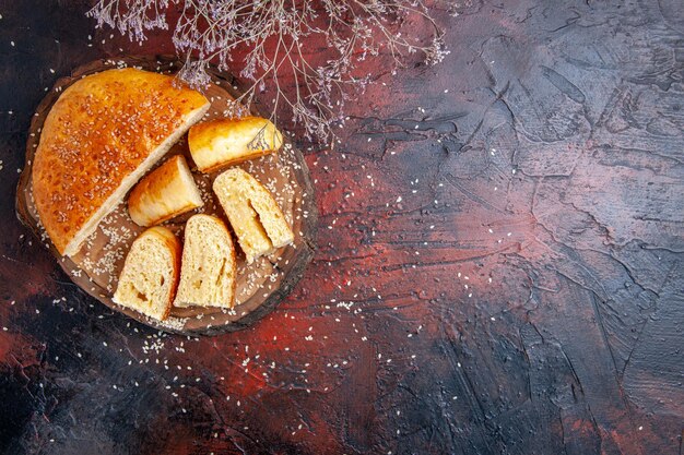 Vue de dessus de la pâtisserie sucrée coupée en morceaux sur une surface sombre