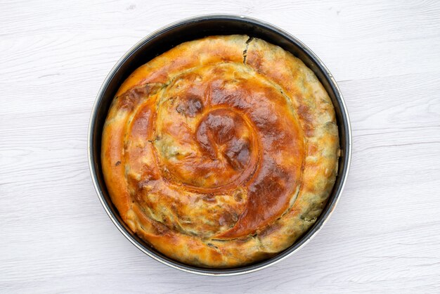 Vue de dessus pâtisserie verte cuite ronde à l'intérieur de la casserole noire sur le fond blanc repas de bureau nourriture pâtisserie déjeuner verts