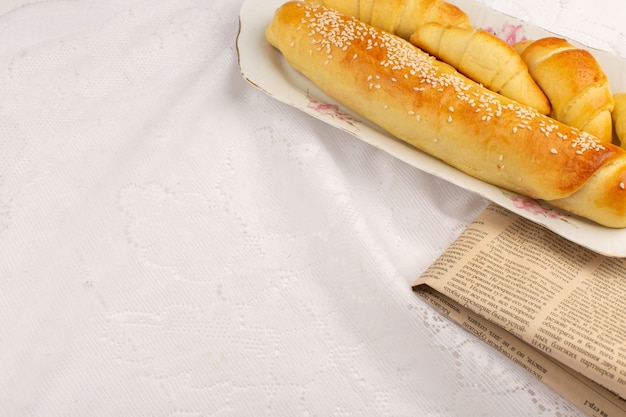 Vue de dessus des pâtisseries avec des croissants à l'intérieur de la plaque sur le sol blanc