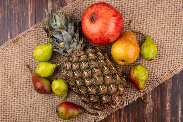 Vue de dessus des pêches d'ananas et de grenade autour sur un sac et une surface en bois