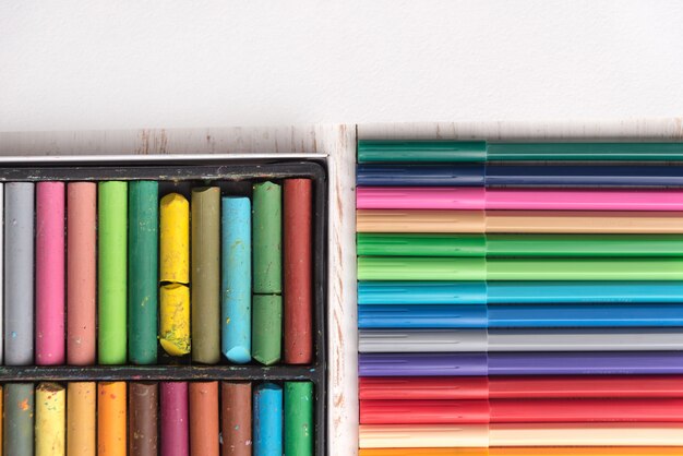 Vue de dessus de la peinture pastel et des marqueurs dans des boîtes sur la table