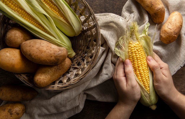 Vue de dessus de la personne qui épluche le maïs avec des pommes de terre