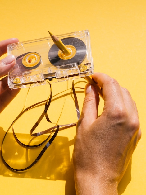 Vue de dessus d'une personne réparant une cassette avec un crayon