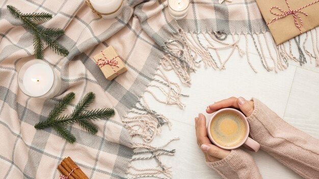 Vue de dessus de la personne tenant la tasse avec des bougies et une couverture