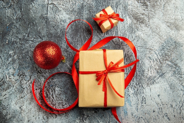 Vue de dessus petit cadeau attaché avec une boule de Noël ruban rouge sur fond sombre