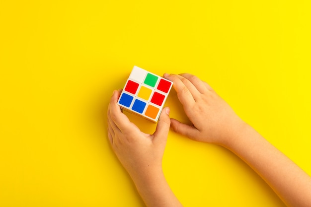 Vue de dessus petit enfant jouant avec un cube de rubis sur une surface jaune