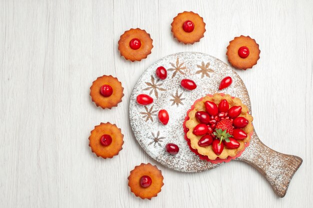 Vue de dessus petit gâteau aux fruits et gâteaux sur un bureau blanc