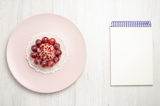 Vue de dessus petit gâteau aux raisins à l'intérieur de la plaque sur le tableau blanc, gâteau dessert aux fruits