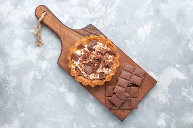 Vue de dessus petit gâteau crème avec des barres de chocolat sur le fond blanc gâteau sucré sucre crème chocolat