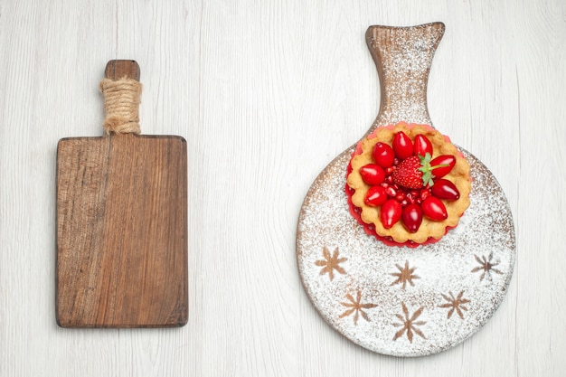 Vue de dessus petit gâteau crémeux aux fruits frais sur un bureau blanc