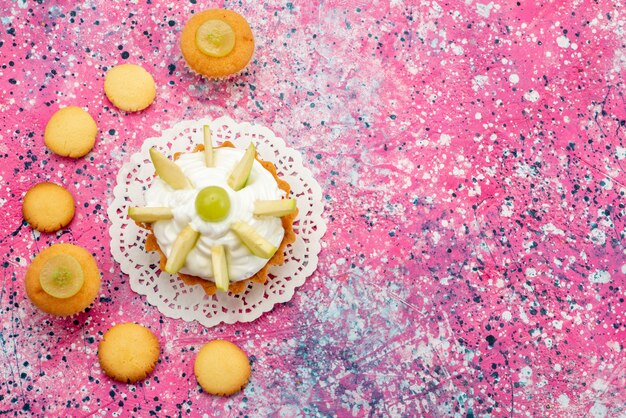 Vue de dessus petit gâteau crémeux avec des biscuits aux fruits tranchés sur le gâteau de bureau coloré photo couleur sucre sucré