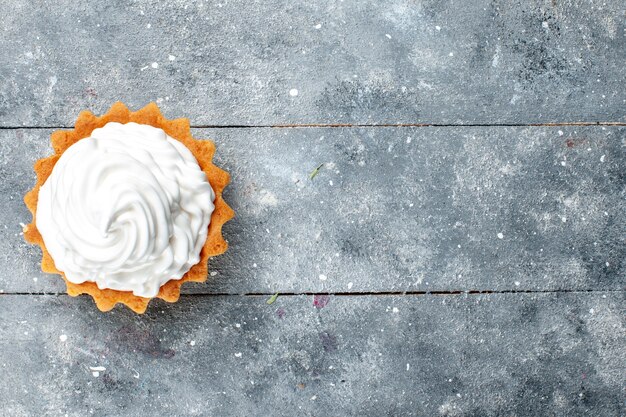 Vue de dessus petit gâteau crémeux cuit délicieux isolé sur fond gris gâteau biscuit sucre sucré