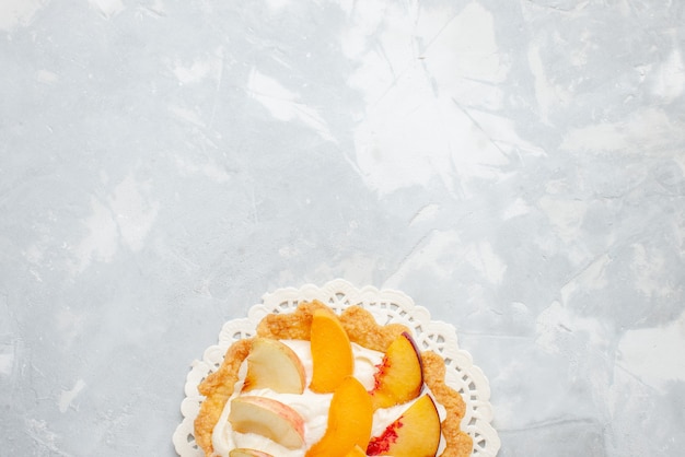 Vue de dessus petit gâteau crémeux avec des fruits tranchés dessus sur le bureau blanc-lumière gâteau aux fruits biscuit sucré goût de biscuit