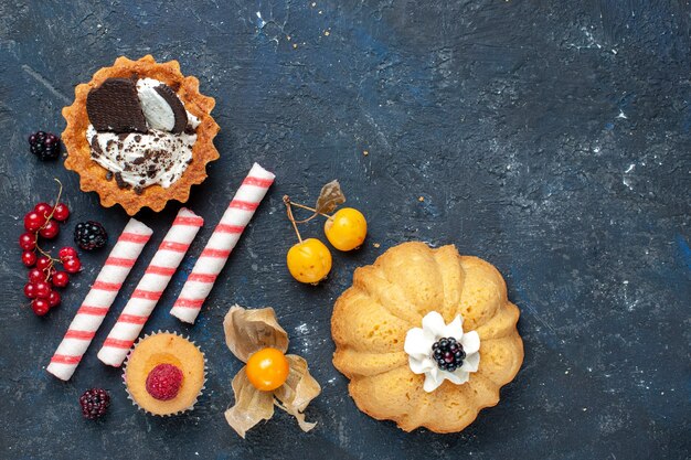 Vue de dessus petit gâteau délicieux avec des biscuits et des bonbons de bâton rose fruits sur le bureau sombre biscuit gâteau aux fruits sucrés