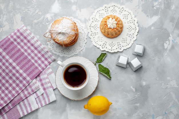 Vue de dessus petit gâteau délicieux avec des biscuits sandwich au thé et citron aigre sur la couleur de biscuit biscuit gâteau biscuit