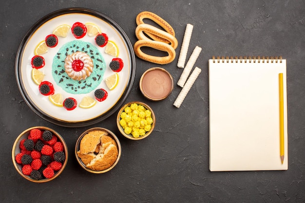 Vue de dessus petit gâteau délicieux avec des bonbons et des tranches de citron sur fond sombre gâteau biscuit aux agrumes biscuit sucré