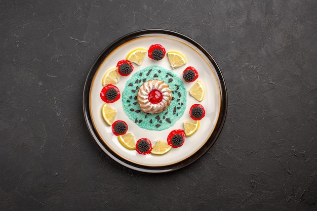 Vue de dessus petit gâteau délicieux avec confitures et tranches de citron à l'intérieur de la plaque sur fond sombre biscuit aux agrumes aux fruits biscuit sucré