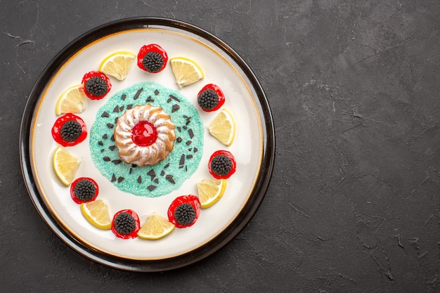 Vue de dessus petit gâteau délicieux avec confitures et tranches de citron à l'intérieur de la plaque sur fond sombre biscuit aux agrumes aux fruits biscuit sucré