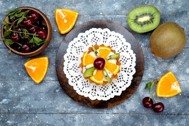 Une vue de dessus petit gâteau délicieux avec de la crème et des fruits frais tranchés sur le thé au sucre gâteau de bureau gris