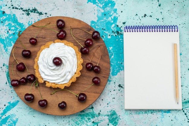 Photo gratuite vue de dessus petit gâteau délicieux avec de la crème et des fruits sur le gâteau de table bleu-lumière crème douce cuire le thé aux fruits