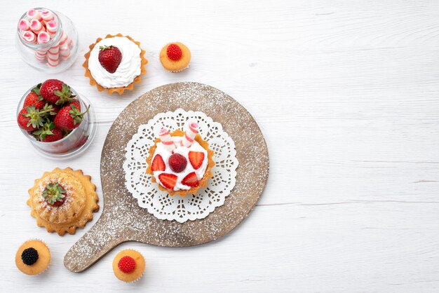 Vue de dessus petit gâteau délicieux avec de la crème et des gâteaux de fraises en tranches sur le fond blanc gâteau berry cuire au four aux fruits