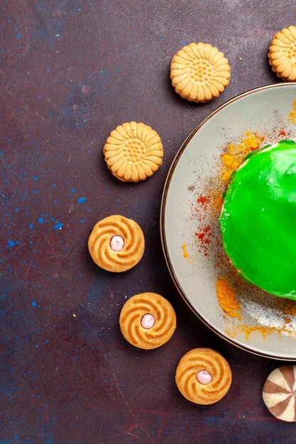 Vue de dessus petit gâteau délicieux avec différents petits biscuits sur une surface sombre