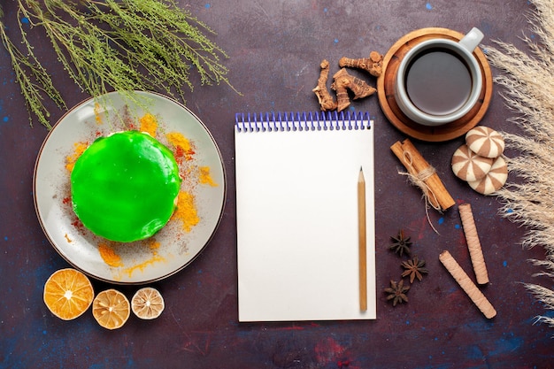 Vue de dessus petit gâteau délicieux avec une tasse de thé sur un bureau violet foncé