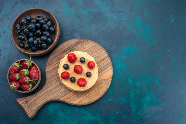 Vue de dessus petit gâteau rond formé de fraises fraîches sur la surface bleu foncé