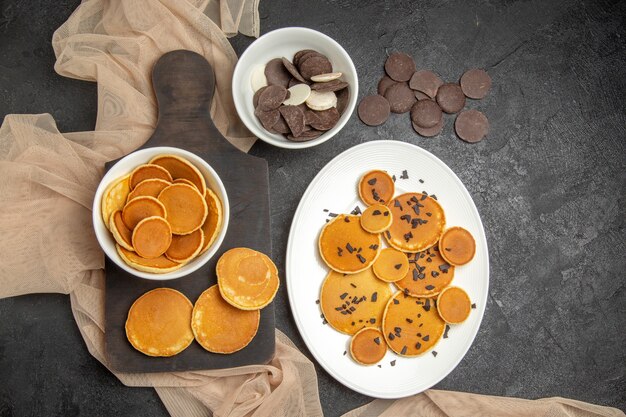 Vue de dessus de petites crêpes avec des cookies sur le gris foncé