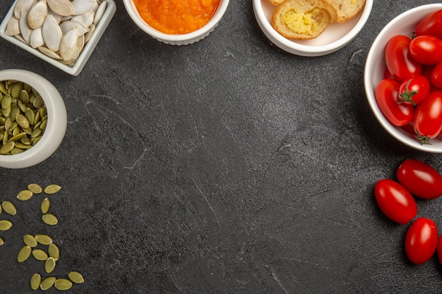 Vue de dessus de petites tomates fraîches avec des graines et de la citrouille en purée sur la couleur mûre des graines de fond gris