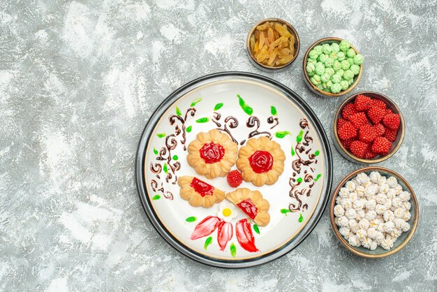 Vue de dessus de petits biscuits au sucre avec des bonbons sur blanc