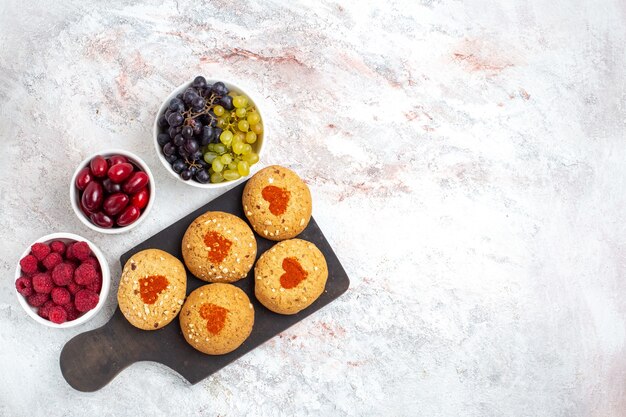 Vue de dessus petits biscuits au sucre délicieux bonbons pour le thé avec des fruits sur un fond blanc biscuit tarte biscuit au sucre gâteau sucré