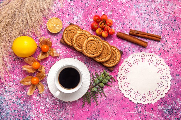 Vue de dessus de petits biscuits délicieux avec du thé au citron et de la cannelle sur la surface rose clair