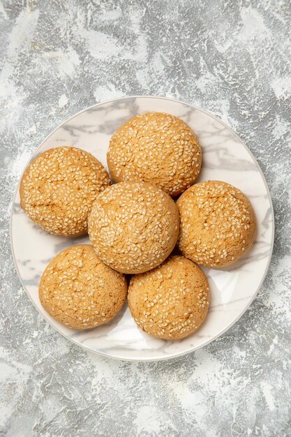 Vue de dessus de petits biscuits moelleux délicieux dessert pour le thé à l'intérieur d'une assiette sur une surface blanche