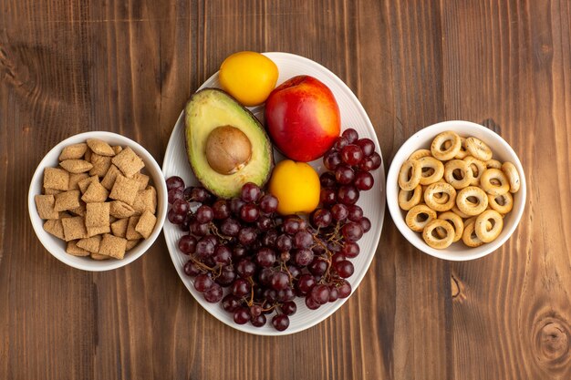 Vue de dessus petits biscuits d'oreiller avec des craquelins et des fruits sur le bureau brun