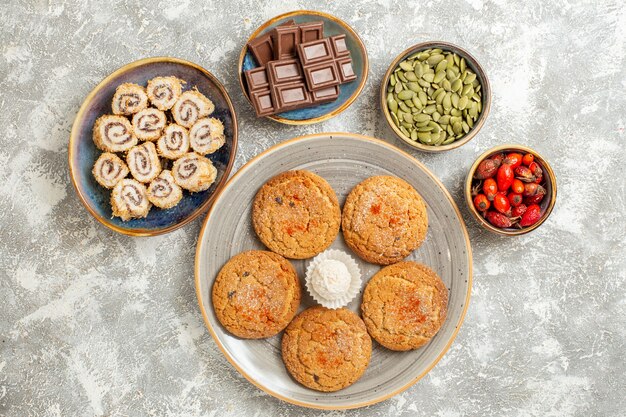 Vue de dessus de petits bonbons avec des biscuits sur fond blanc