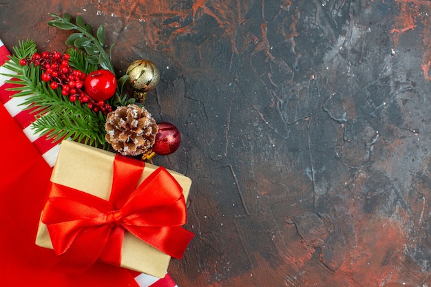 Vue de dessus de petits cadeaux attachés avec une branche d'arbre de Noël de ruban rouge sur le lieu de copie de table rouge foncé