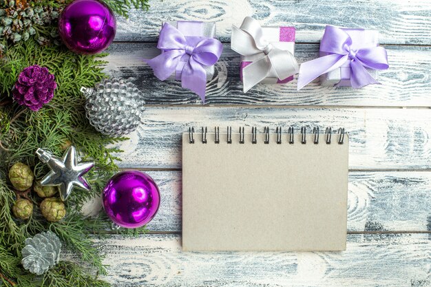 Vue de dessus petits cadeaux jouets d'arbre de noël branches de sapin cahier sur une surface en bois