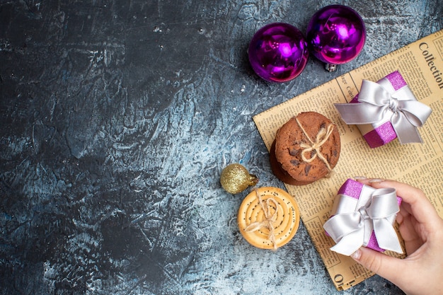 Vue de dessus de petits cadeaux de Noël avec des biscuits et des jouets sur fond clair-foncé