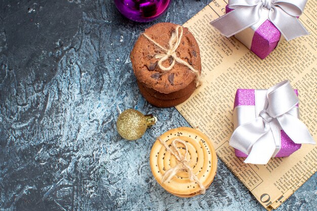 Vue de dessus de petits cadeaux de Noël avec des biscuits et des jouets sur fond clair-foncé