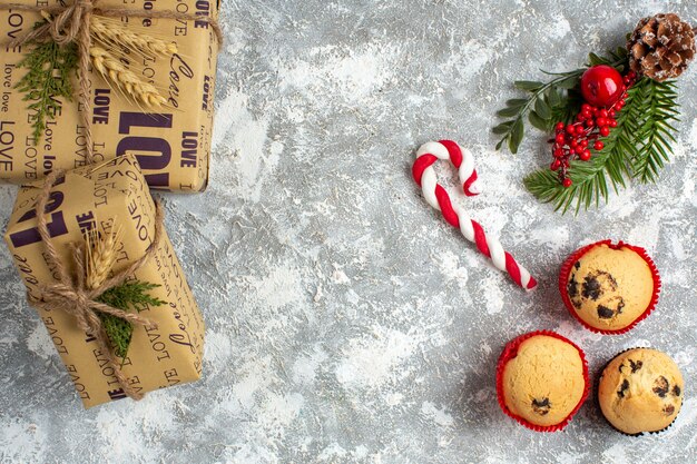 Vue de dessus de petits cupcakes bonbons et branches de sapin accessoires de décoration et cadeaux sur la surface de la glace