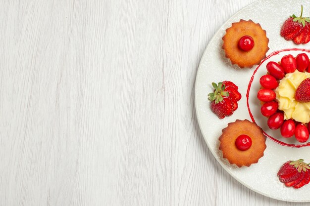 Vue de dessus petits gâteaux aux fruits à l'intérieur de la plaque sur un bureau blanc